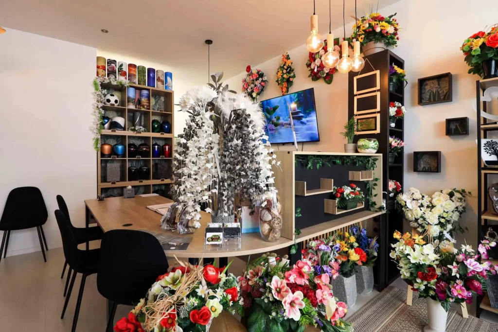 Espace d'accueil funéraire chaleureux avec urnes et fleurs de deuil.